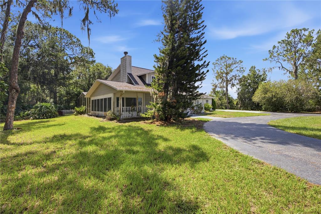 A two-story house with a screened-in porch and a paved driveway sits on a lawn — 15324 BALM WIMAUMA ROAD, WIMAUMA, FL