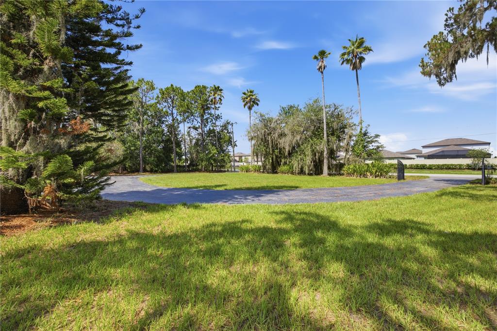 A paved circular driveway sits in front of a grassy lawn with various trees — 15324 BALM WIMAUMA ROAD, WIMAUMA, FL