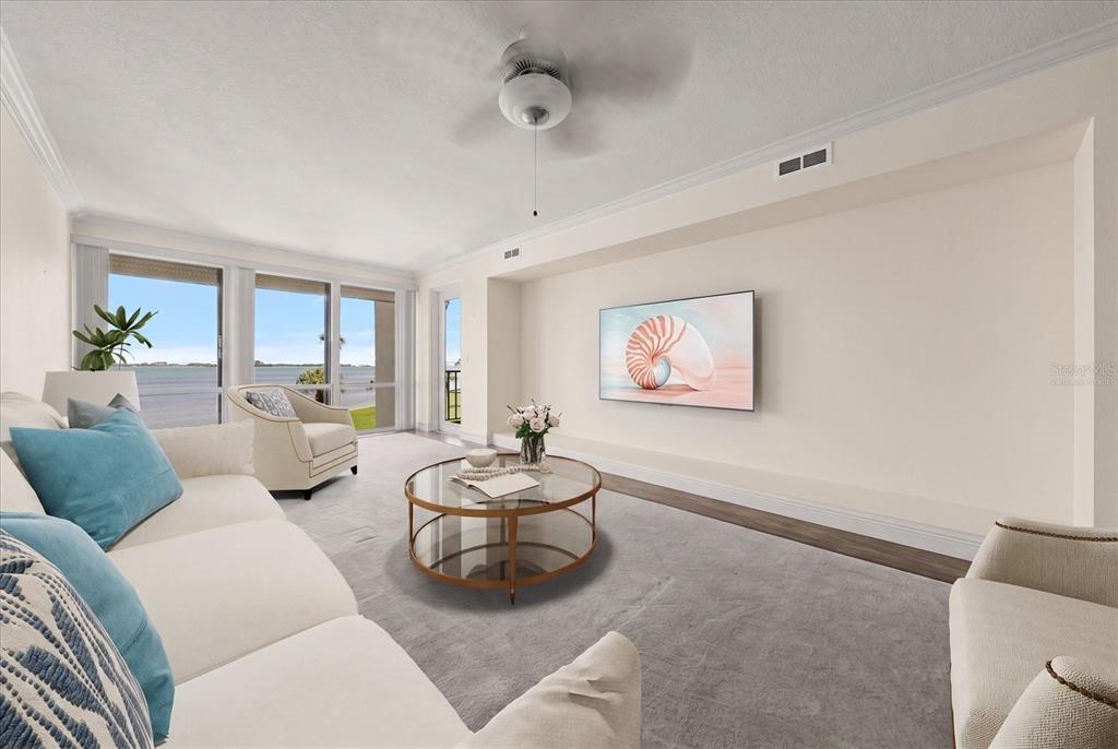 A living room features a white sofa, a glass coffee table, and a wall-mounted television — 50 COE ROAD UNIT 123, BELLEAIR, FL