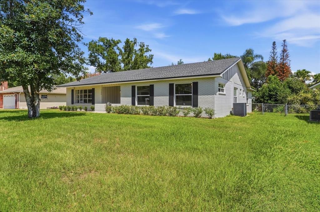 A single-story white brick house with a dark shingled roof and a front lawn — 1308 GLENFORD LANE, LAKELAND, FL