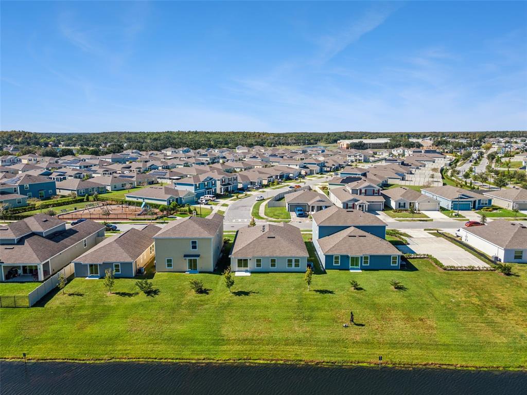 An aerial view shows a row of suburban houses with backyards facing a small pond — 2009 MYRTLE PINE STREET, KISSIMMEE, FL