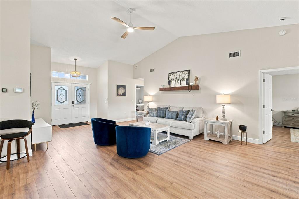 A living room features light wood flooring, a vaulted ceiling, and two blue velvet chairs — 1236 FLORA VISTA STREET, TRINITY, FL