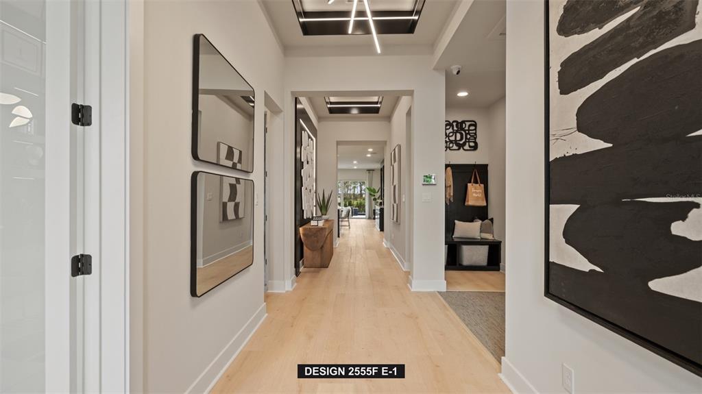 A bright hallway features light wood flooring, modern light fixtures, and black-framed wall art — 9515 SANDY SHORES STREET, PARRISH, FL