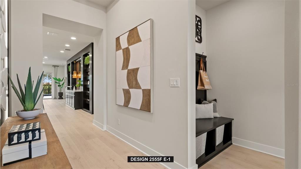 A bright entryway features light wood flooring, a geometric wall painting, and a built-in bench — 9515 SANDY SHORES STREET, PARRISH, FL
