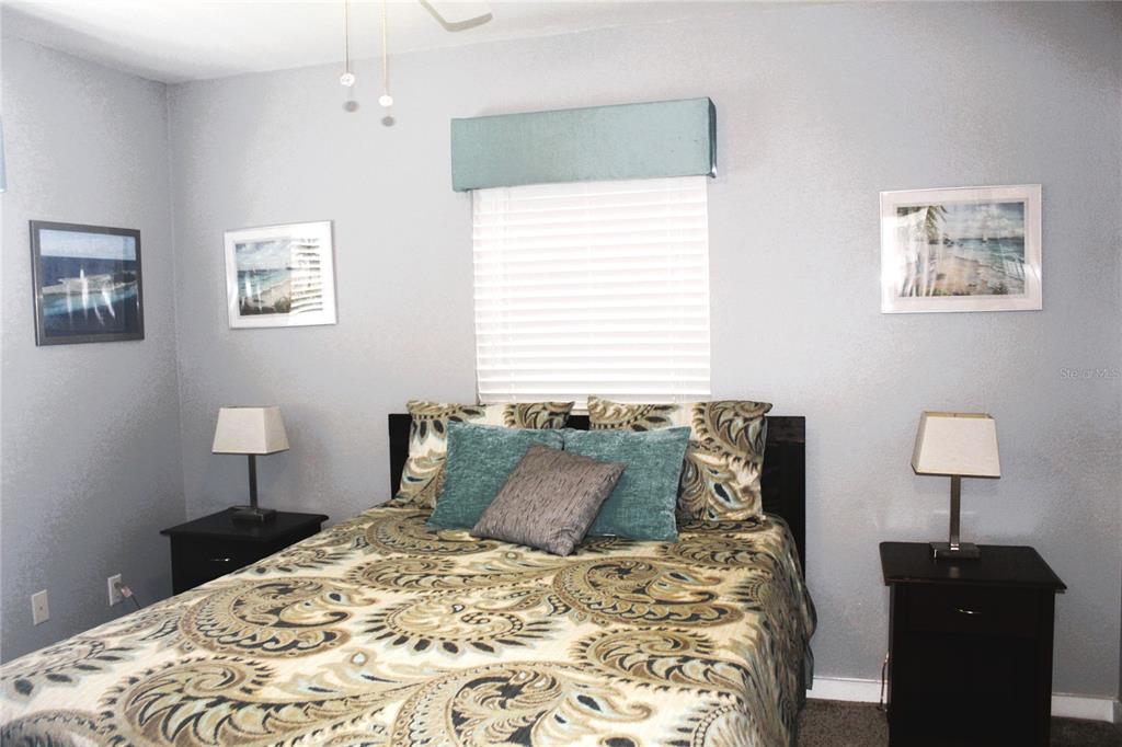 A bedroom features a patterned bedspread, two nightstands with lamps, and framed wall art — 12400 PARK BLVD UNIT 206, SEMINOLE, FL