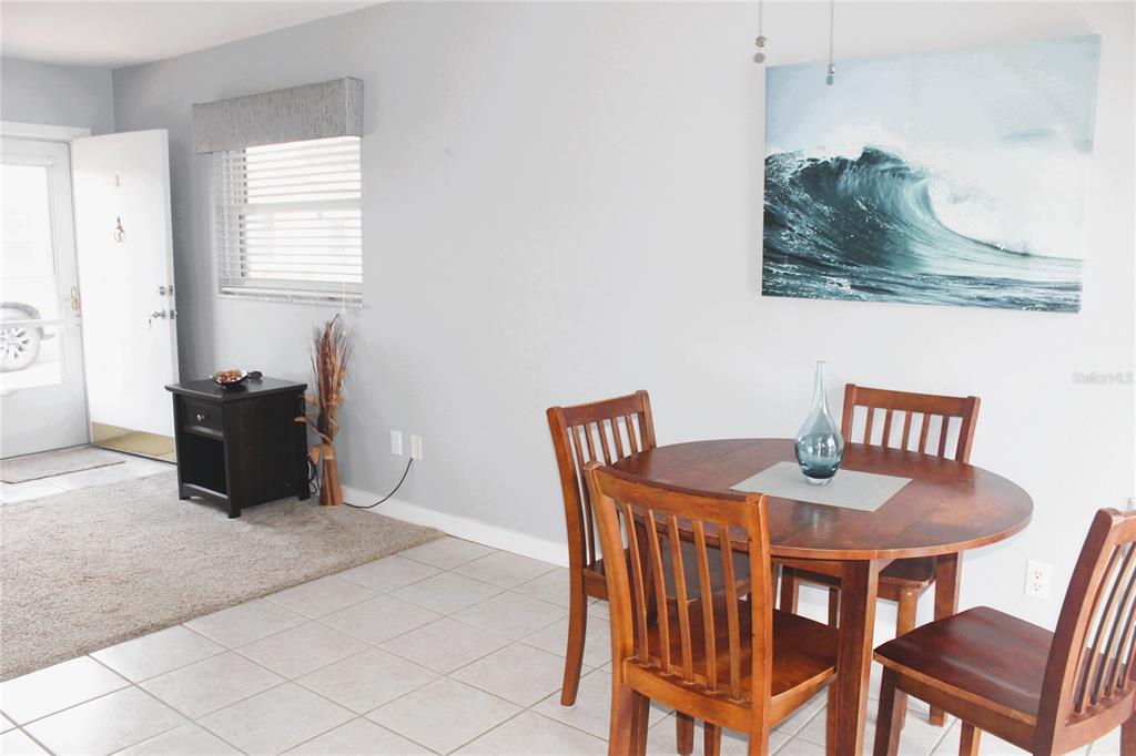 A dining area with a wooden table and chairs sits next to a carpeted entryway — 12400 PARK BLVD UNIT 206, SEMINOLE, FL