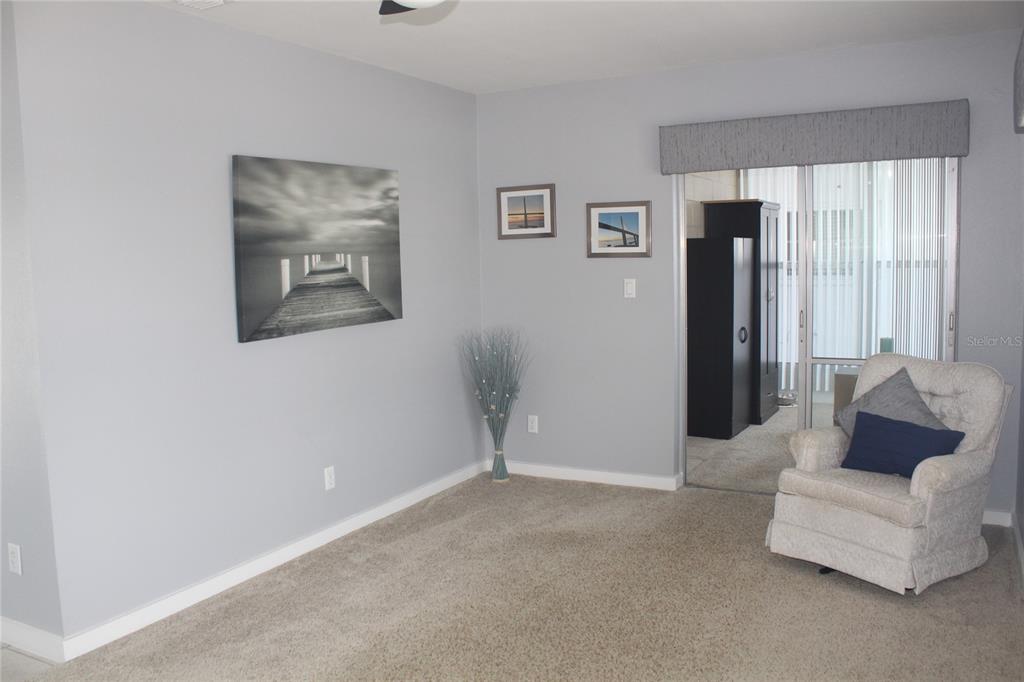 A carpeted living room features gray walls, a pier wall art piece, and an armchair — 12400 PARK BLVD UNIT 206, SEMINOLE, FL