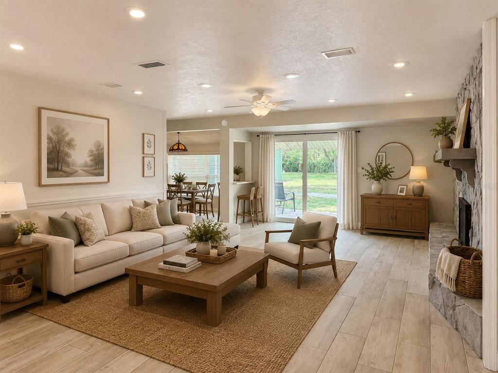 A living room features a stone fireplace, light wood flooring, and a sliding glass door — 9628 DAVIS ROAD, TAMPA, FL