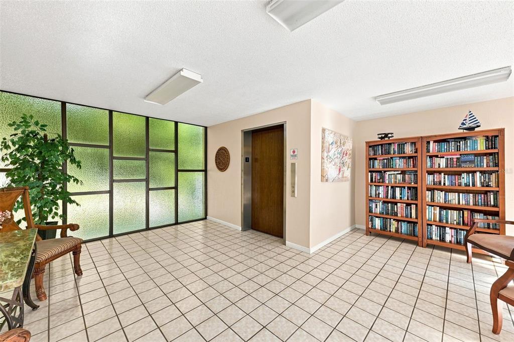 A lobby features a tiled floor, a wooden elevator door, and two tall bookshelves — 2650 PEARCE DRIVE UNIT 309, CLEARWATER, FL
