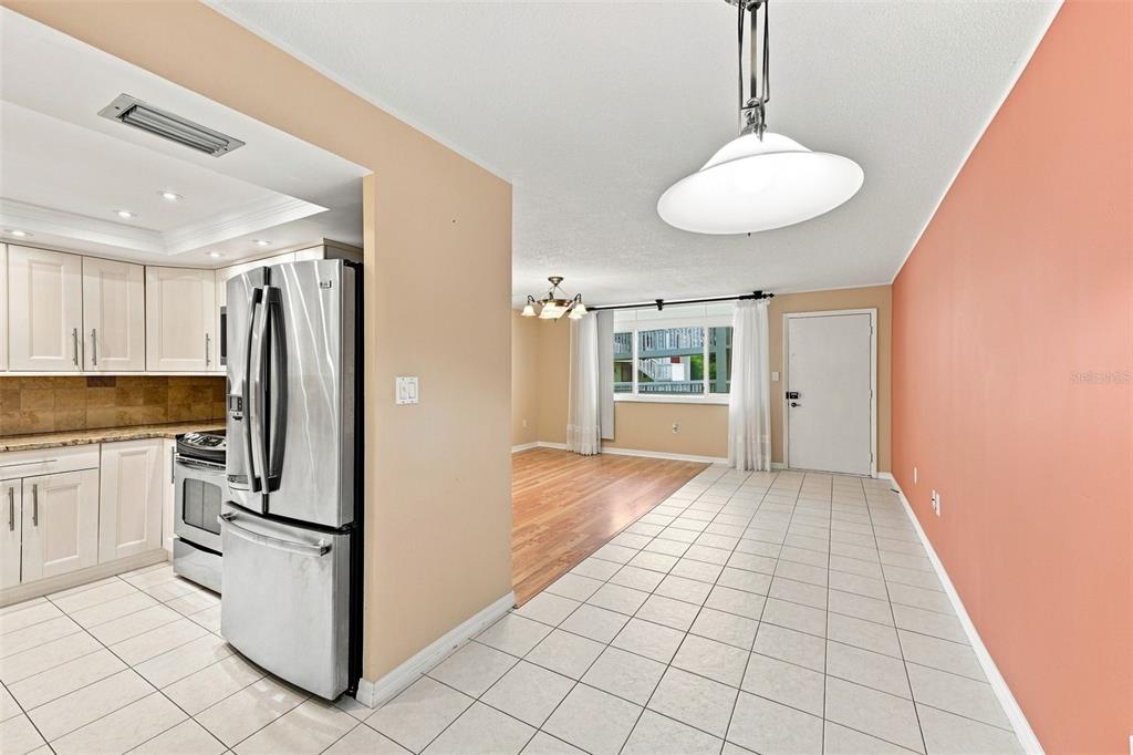 A kitchen with white cabinets and stainless steel appliances opens into a tiled dining area — 2650 PEARCE DRIVE UNIT 309, CLEARWATER, FL