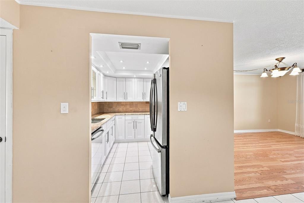 A view through a doorway into a white kitchen with a stainless steel refrigerator — 2650 PEARCE DRIVE UNIT 309, CLEARWATER, FL