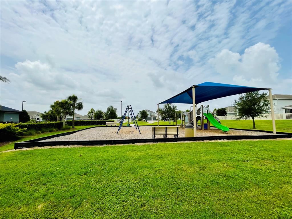 A playground with a swing set and a covered slide sits on a gravel lot — 436 LEMONGRASS ROAD, MINNEOLA, FL