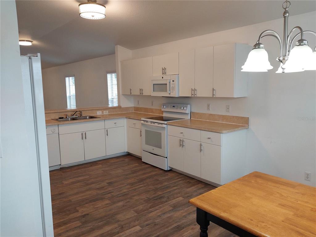A kitchen with white cabinets, laminate countertops, and wood-look flooring — 557 WINDERMERE DRIVE, LEHIGH ACRES, FL