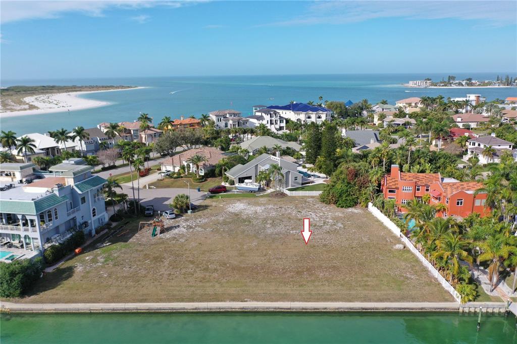 An aerial view shows a vacant waterfront lot situated between two large residential homes — GALEON DRIVE, TIERRA VERDE, FL