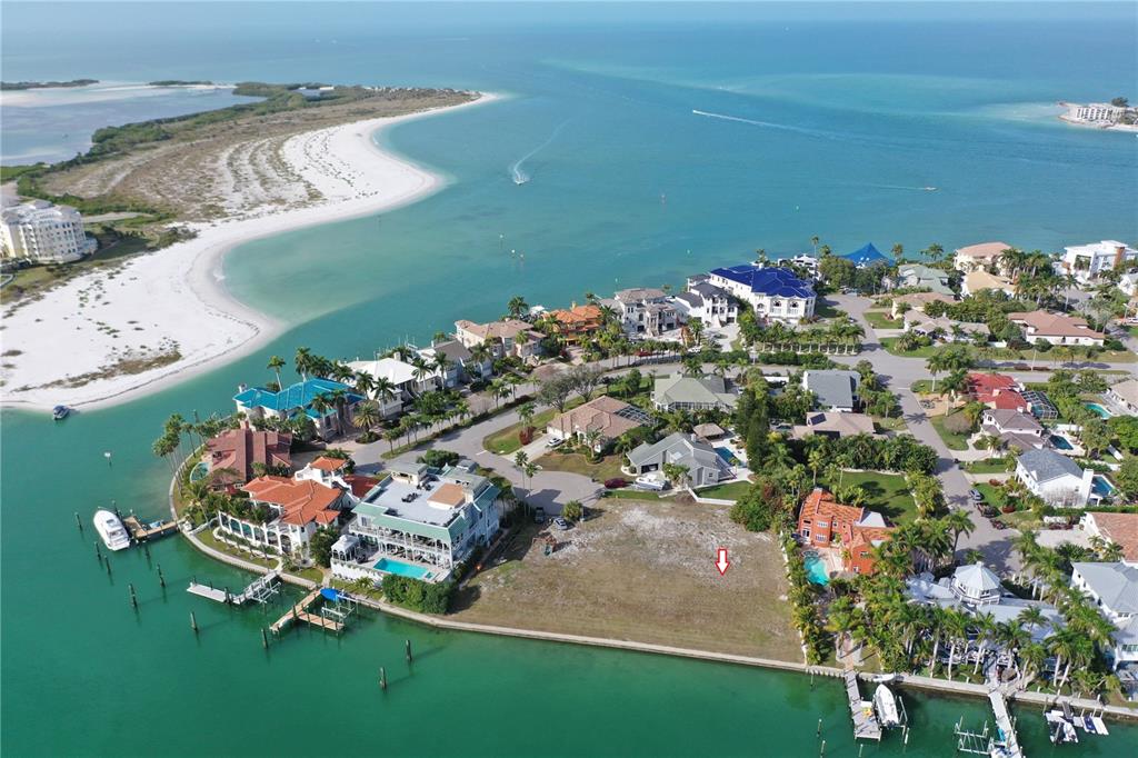 An aerial view shows a vacant waterfront lot surrounded by luxury homes and turquoise water — GALEON DRIVE, TIERRA VERDE, FL