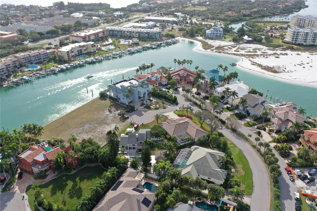An aerial view shows waterfront luxury homes, a canal with docked boats, and nearby apartment complexes — GALEON DRIVE, TIERRA VERDE, FL