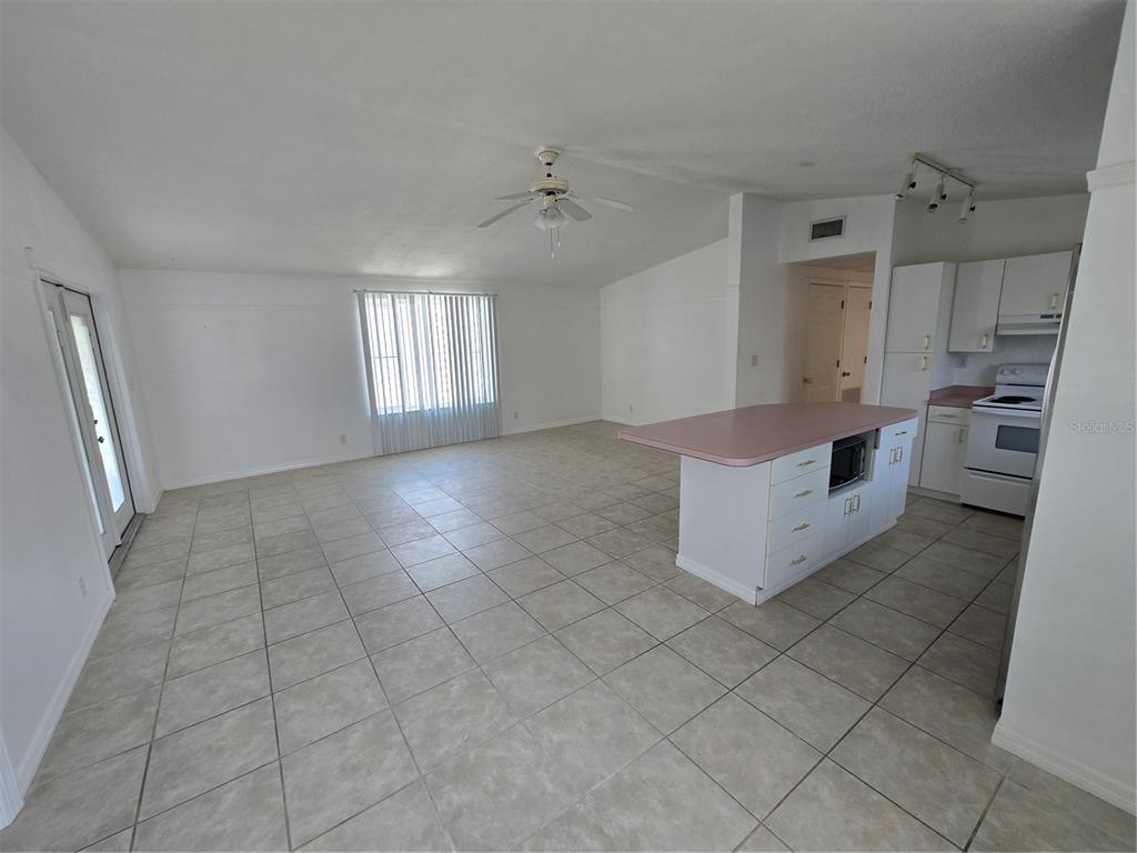 A covered wooden deck features a small bistro set and double glass doors — 2804 AVENUE C, HOLMES BEACH, FL