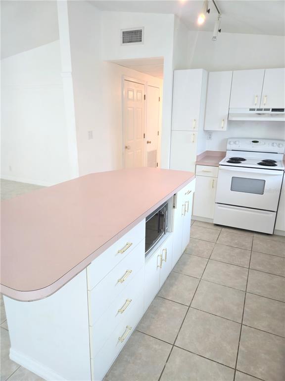 An open-concept living room and kitchen featuring floral sofas, a wooden coffee table, and island — 2804 AVENUE C, HOLMES BEACH, FL