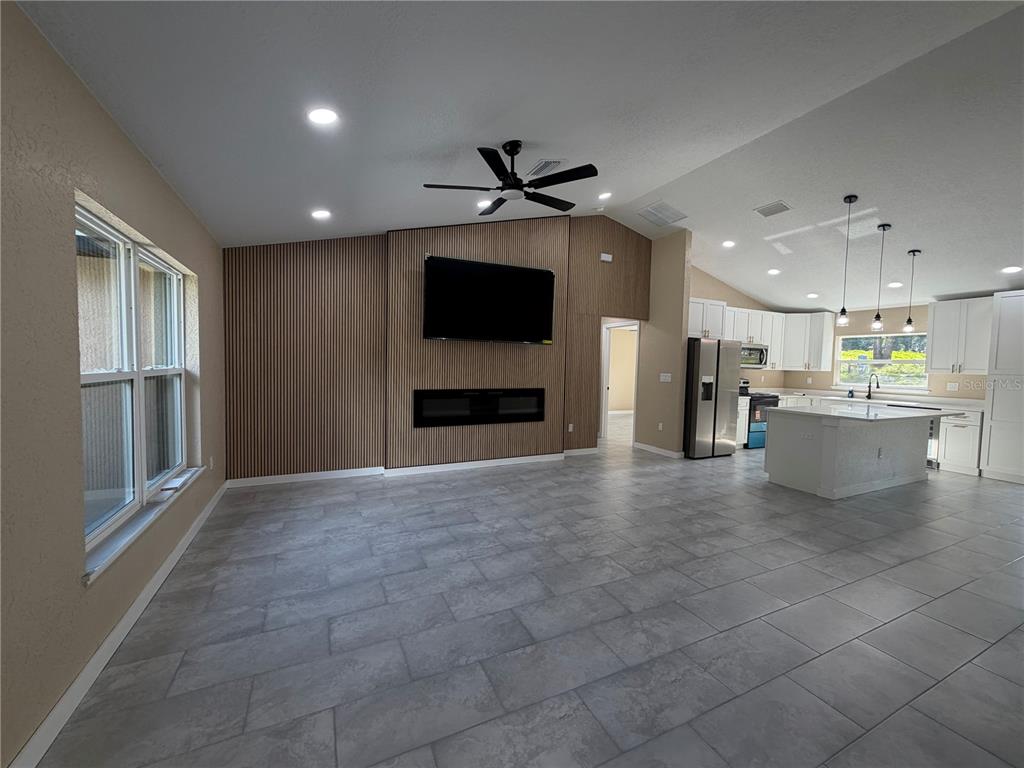 An open-concept living room features a slatted wood accent wall with a fireplace and television — 13268 SE 44TH CT, BELLEVIEW, FL