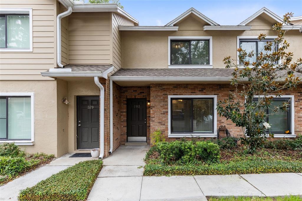 Two adjacent townhome entrances with brick and tan siding exteriors and concrete walkways — 283 SANDLEWOOD TRAIL UNIT 3, WINTER PARK, FL