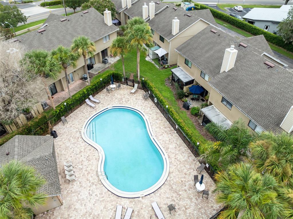 An aerial view shows a community swimming pool surrounded by a patio and residential townhomes — 283 SANDLEWOOD TRAIL UNIT 3, WINTER PARK, FL