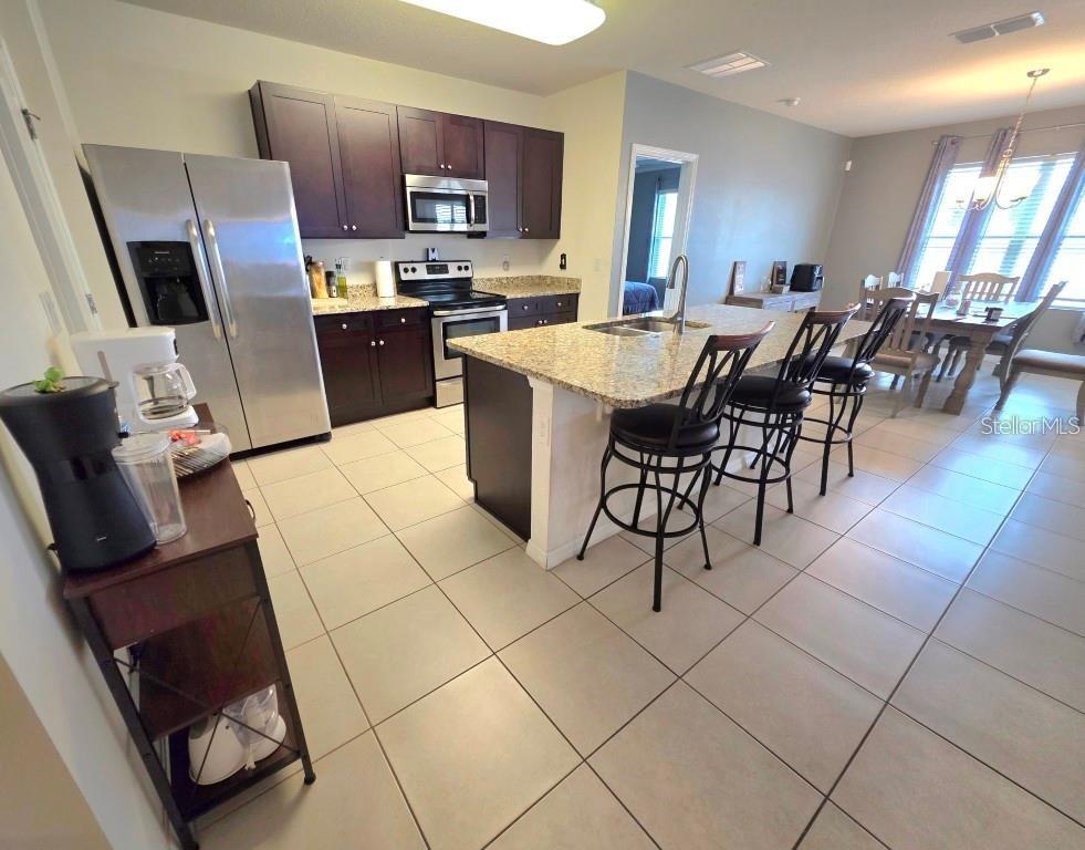 A kitchen with dark cabinets, granite countertops, stainless steel appliances, and a central island — 368 ABERDEEN DRIVE, DAVENPORT, FL