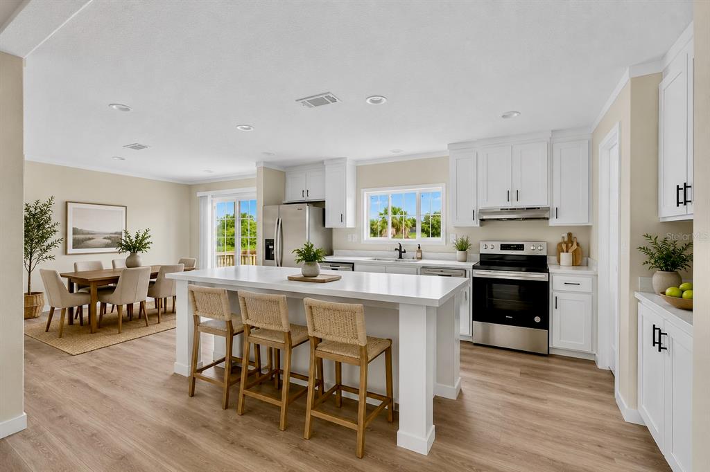A bright kitchen features white cabinets, a large island with bar stools, and wood flooring — 16918 NW 264TH STREET, OKEECHOBEE, FL