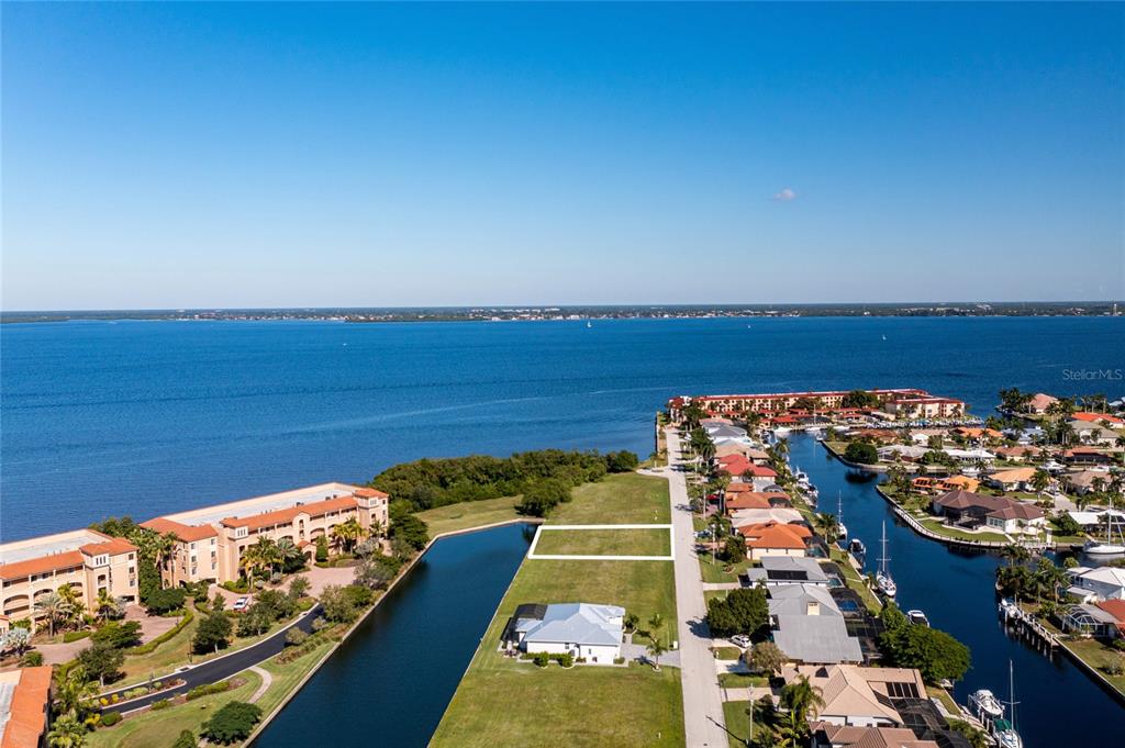 An aerial view shows a vacant rectangular lot situated between a canal and a road — 65 COLONY POINT DRIVE, PUNTA GORDA, FL