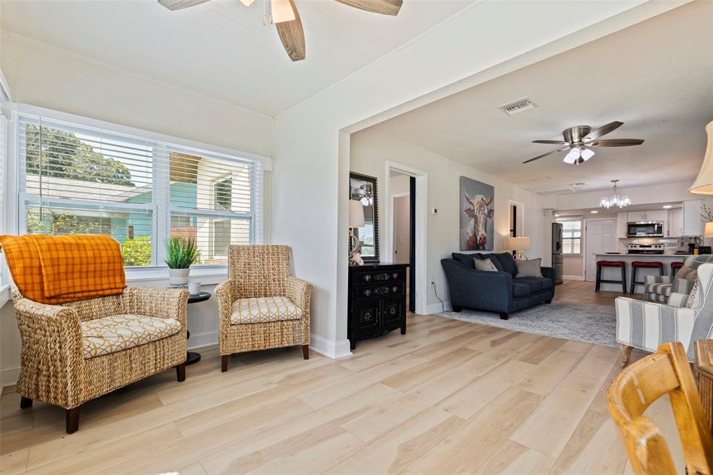 A bright living room features light wood flooring, wicker chairs, and an open-concept kitchen area — 1601 54TH STREET S, GULFPORT, FL