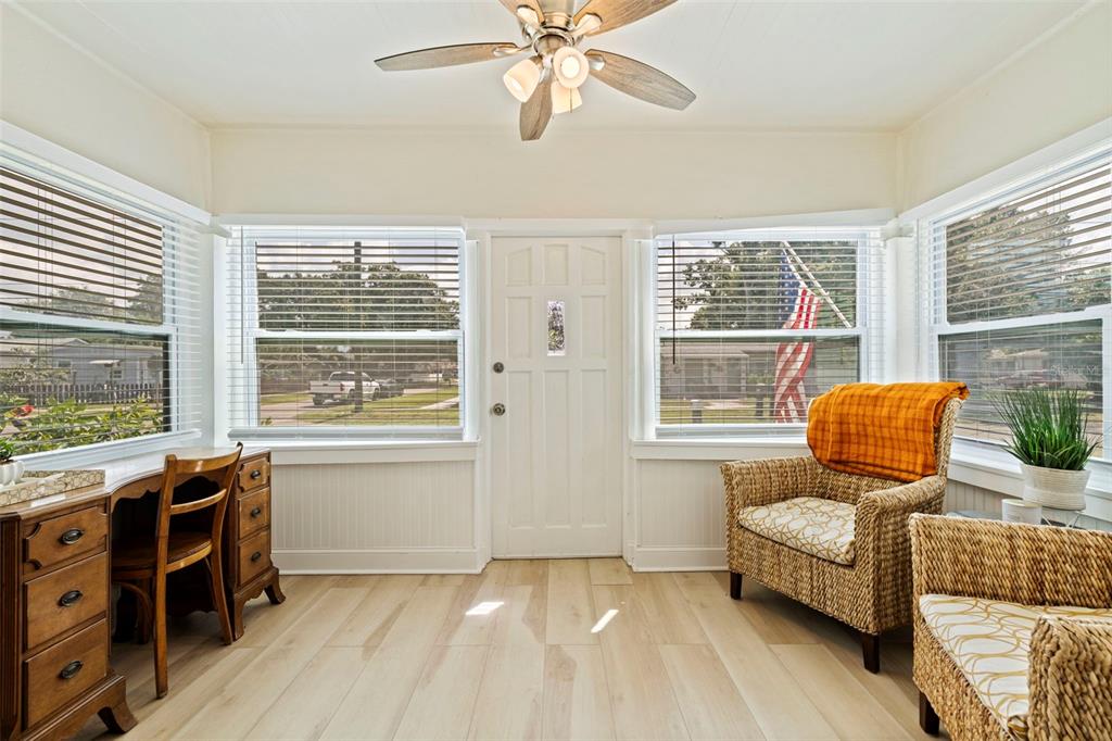 A sunroom features light wood flooring, a ceiling fan, a desk, and two wicker chairs — 1601 54TH STREET S, GULFPORT, FL