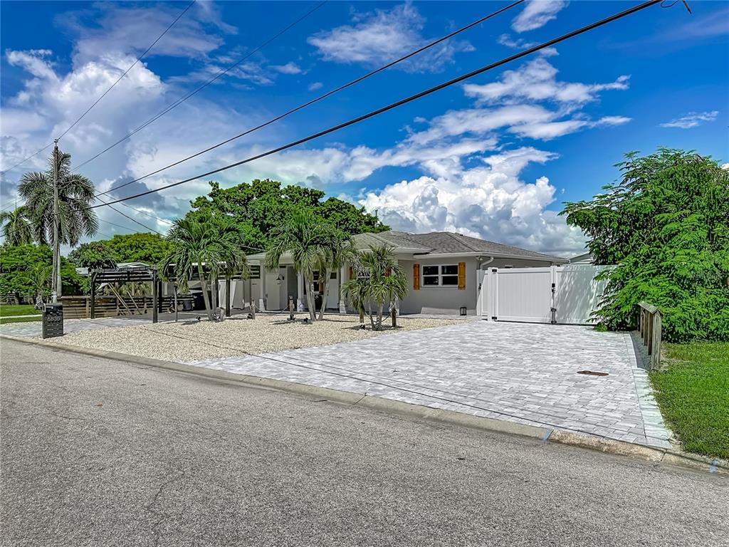 A single-story house with a paved driveway, gravel yard, and white privacy gate — 6835 GEORGIA AVENUE, BRADENTON, FL