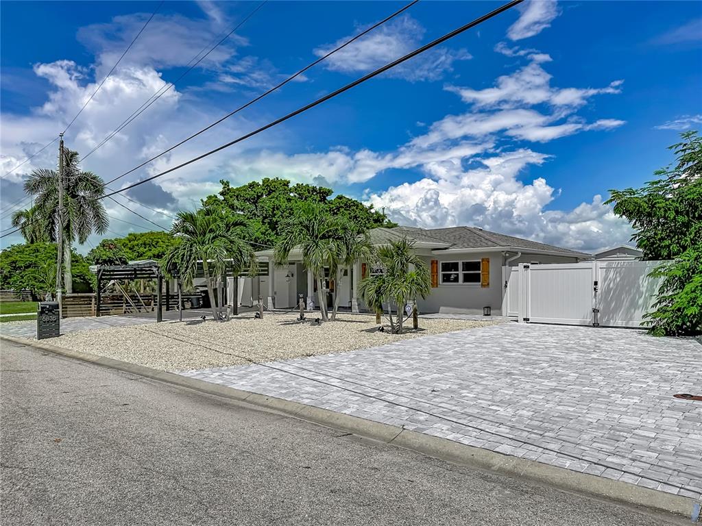 A single-story house with a paved driveway, gravel front yard, and palm trees — 6835 GEORGIA AVENUE, BRADENTON, FL