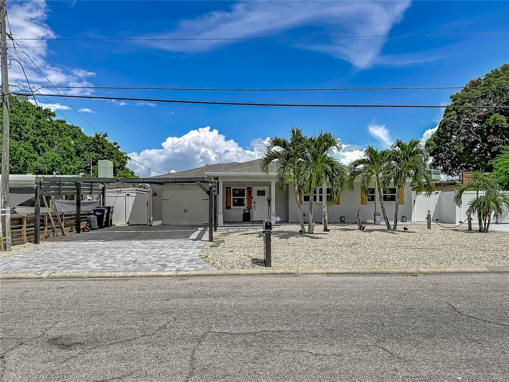 A single-story house with a paved driveway, gravel yard, and palm trees under a blue sky — 6835 GEORGIA AVENUE, BRADENTON, FL