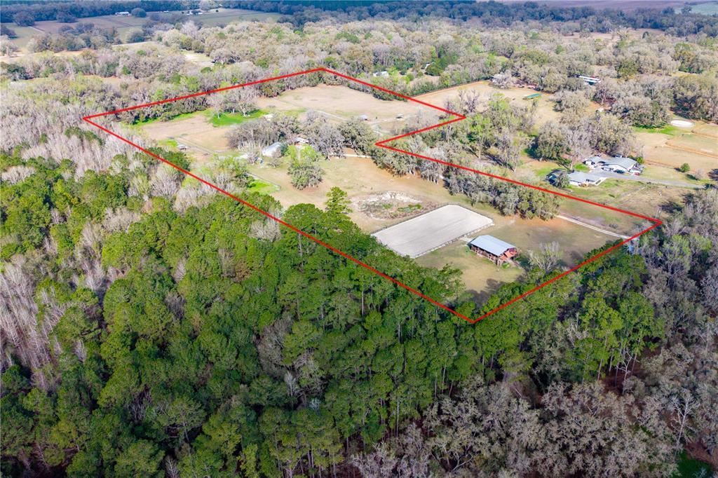An aerial view shows a fenced rural property with a horse arena and barn — 16242 NW 130TH STREET, WILLISTON, FL