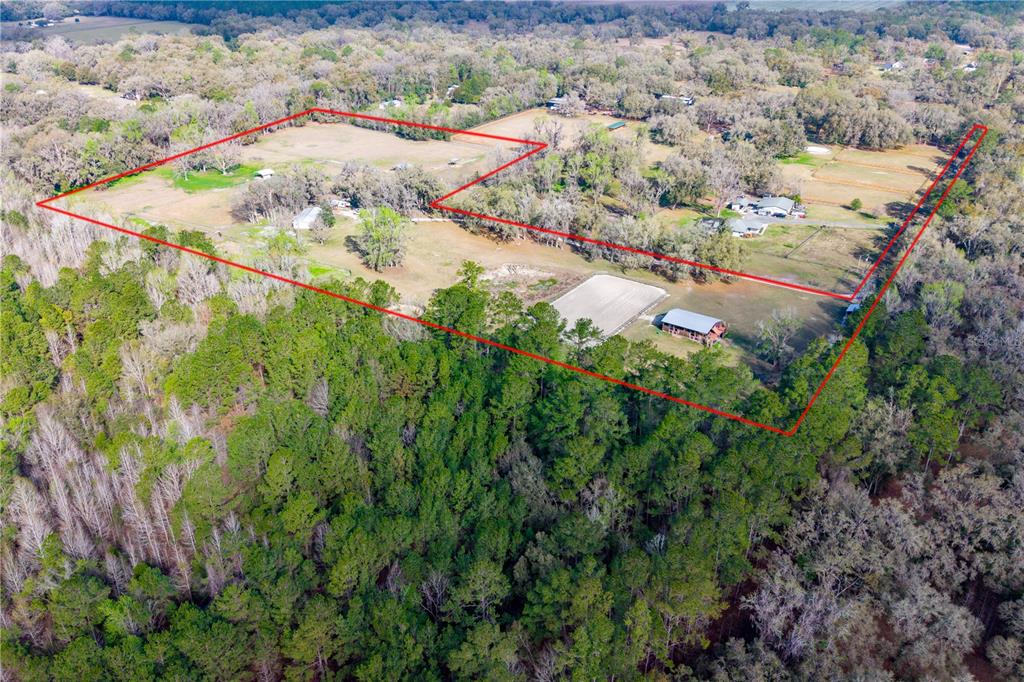 An aerial view shows a rural property with pastures, a barn, and an outdoor riding arena — 16242 NW 130TH STREET, WILLISTON, FL