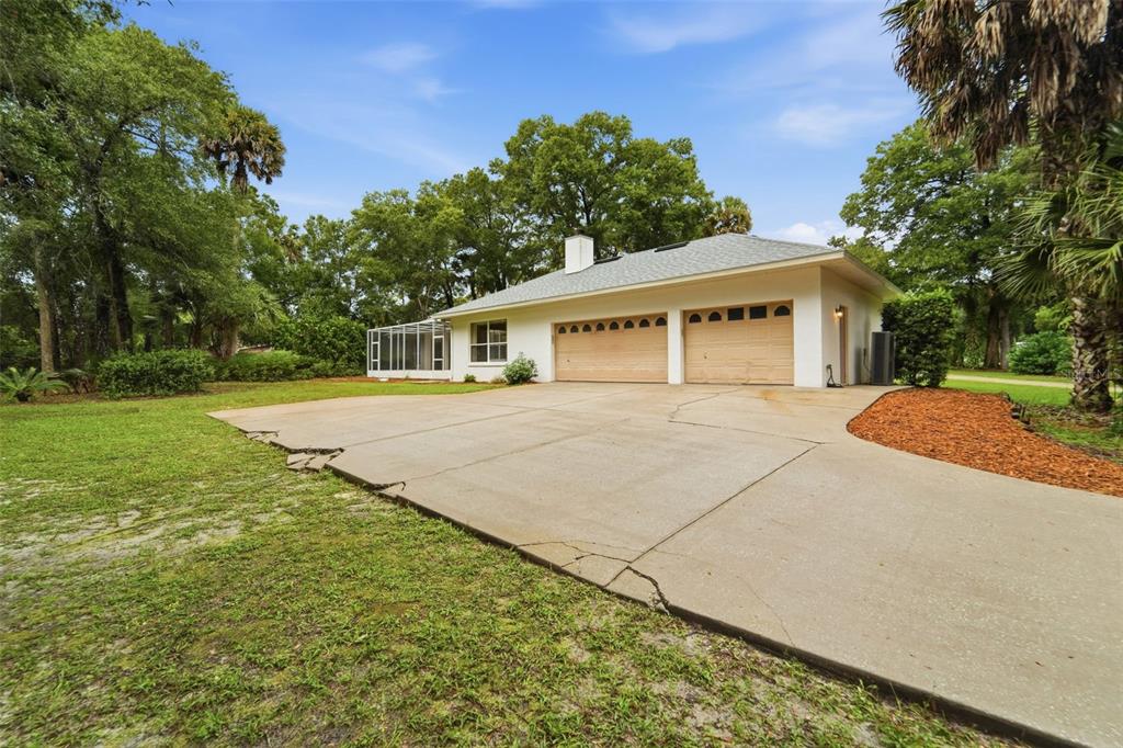 A white house with a two-car garage and a screened-in porch sits on a lot — 1830 GLENWOOD OAKS LANE, DELAND, FL