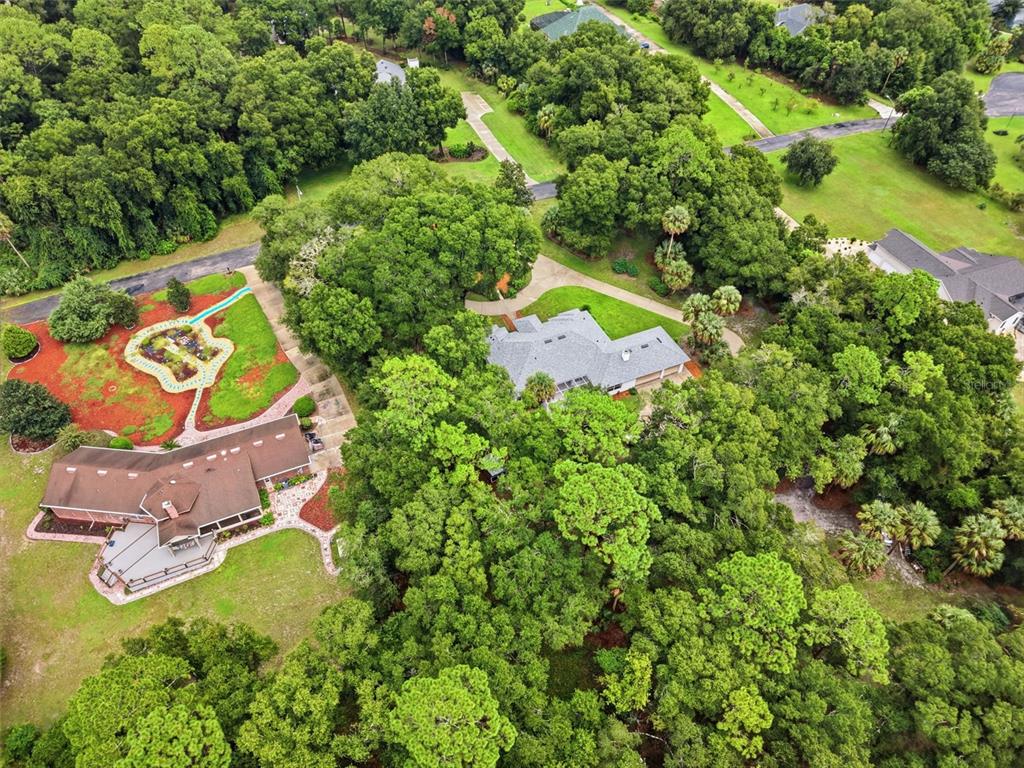 An aerial view shows two houses surrounded by dense trees and landscaped lawns — 1830 GLENWOOD OAKS LANE, DELAND, FL