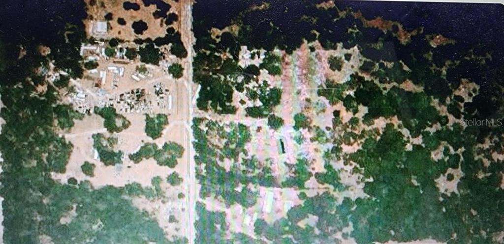 This aerial view shows a wooded plot of land divided by a paved road — 0000 SE THOMAS WAY, LEE, FL