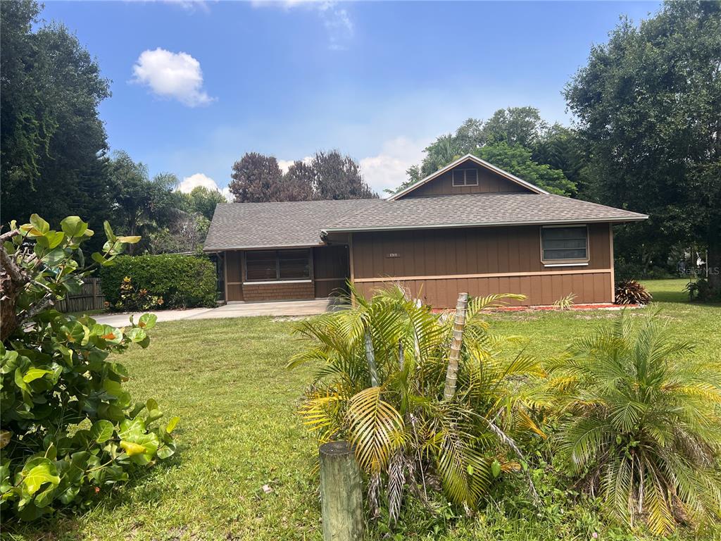 A brown single-story house with a shingled roof sits on a grassy lot with palms — 2919 NICHOLAS ROAD, FORT PIERCE, FL