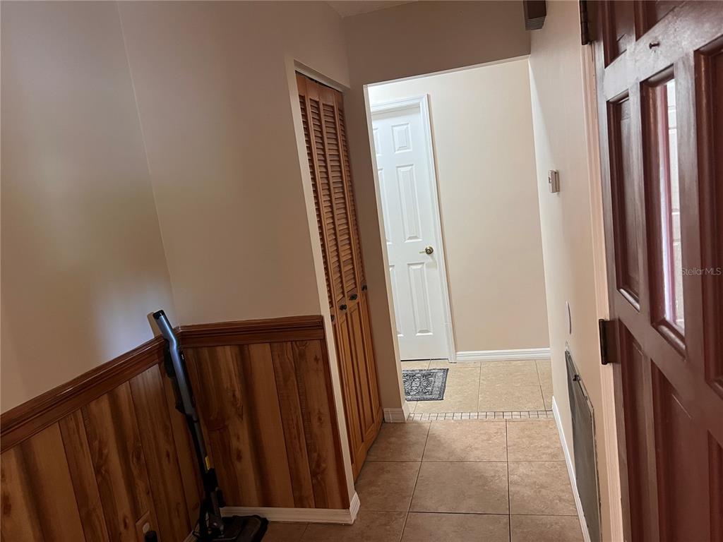 An entryway features wood-paneled wainscoting, louvered closet doors, and tile flooring — 2919 NICHOLAS ROAD, FORT PIERCE, FL