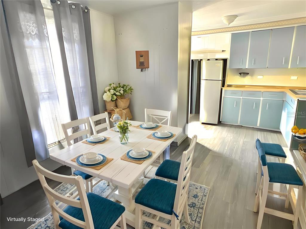 A dining area with a white table and chairs sits adjacent to a blue-cabinet kitchen — 7164 MOUNT GEORGETOWN DRIVE NE UNIT 553, ST PETERSBURG, FL