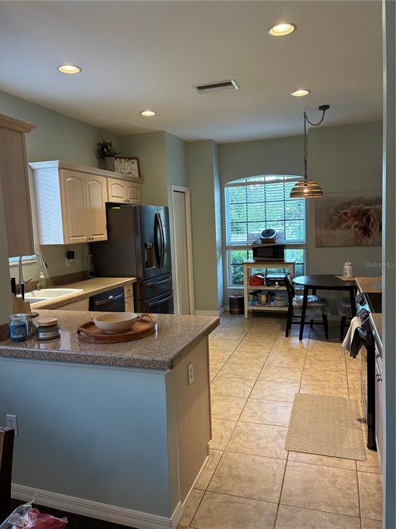 A kitchen features light-colored cabinets, granite countertops, a black refrigerator, and an adjacent dining area — 8872 FOUNDERS CIRCLE, PALMETTO, FL