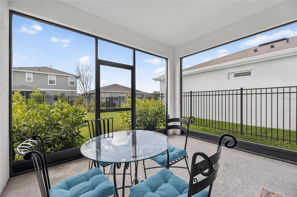 A screened-in patio features a glass-top table, four chairs with blue cushions, and a fenced yard — 6255 GOLDEN BEACH DRIVE, APOLLO BEACH, FL