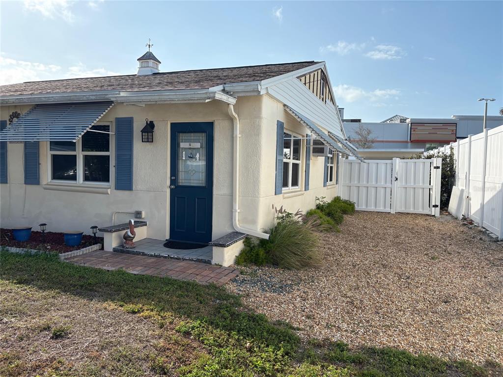 A single-story house with beige stucco walls, blue shutters, and a gravel yard — 111 174TH AVENUE E, REDINGTON SHORES, FL