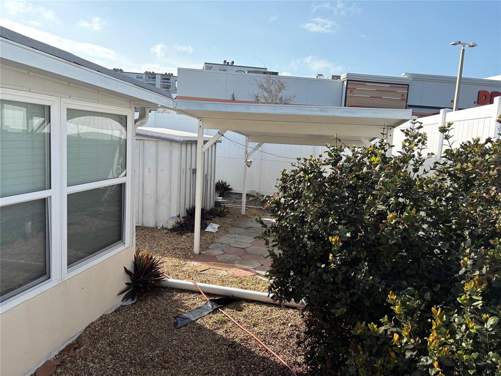 A backyard area features a white metal carport, a small storage shed, and gravel landscaping — 111 174TH AVENUE E, REDINGTON SHORES, FL