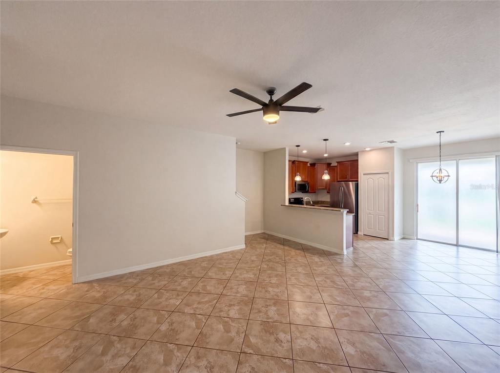 An open-concept living area with tiled floors, a ceiling fan, and an adjacent kitchen — 13717 ROSETTE ROAD, HUDSON, FL