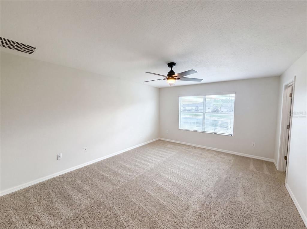 An empty bedroom features beige carpet, white walls, a ceiling fan, and a single window — 13717 ROSETTE ROAD, HUDSON, FL