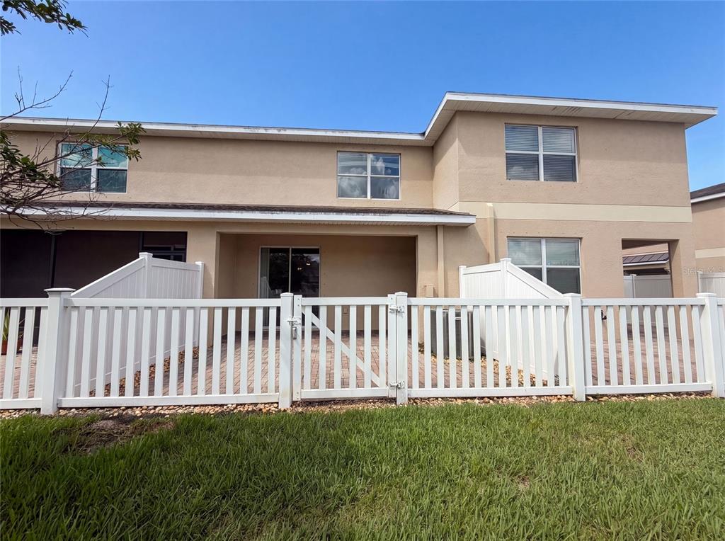 A two-story townhouse exterior features a white picket fence enclosing a small concrete patio — 13717 ROSETTE ROAD, HUDSON, FL