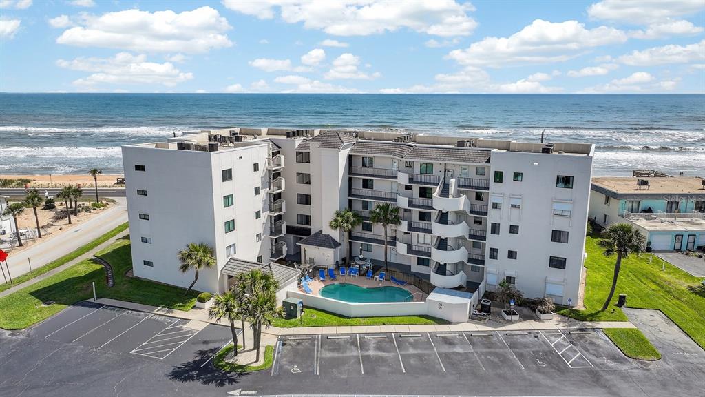 An aerial view shows a multi-story beachfront apartment building with a swimming pool and parking — 2860 OCEAN SHORE BOULEVARD UNIT 2060, ORMOND BEACH, FL