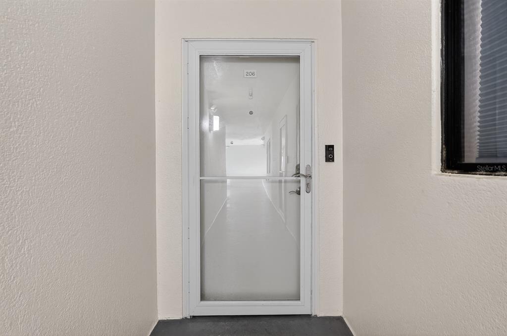 A white storm door with a glass panel leads into a hallway, labeled unit 206 — 2860 OCEAN SHORE BOULEVARD UNIT 2060, ORMOND BEACH, FL